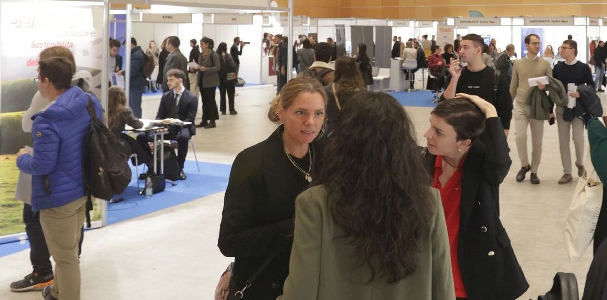 Visione di insieme del padiglione al Palacongressi di Rimini con stand, studenti e referenti delle aziende che parlano e si presentano Visione di insieme del padiglione al Palacongressi di Rimini con stand, studenti e referenti delle aziende che parlano e si presentano
