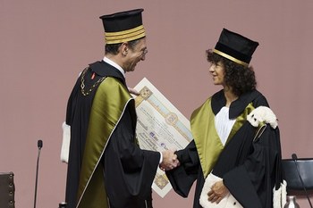 il Magnifico Rettore stringe la mano a Emmanuelle Charpentier - sullo sfondo la pergamena di Laurea